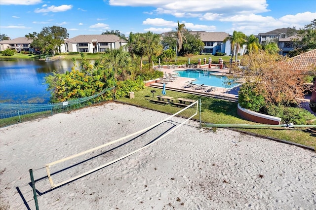 view of home's community with a water view, a pool, and a lawn