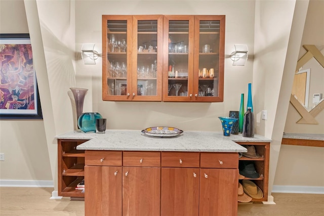 bar featuring light stone counters and light hardwood / wood-style flooring