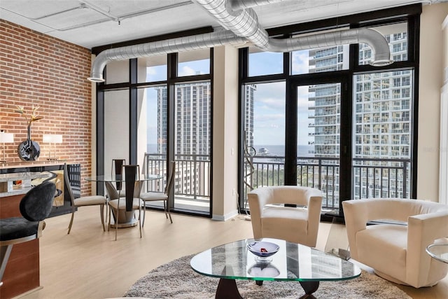 living room featuring light hardwood / wood-style flooring, expansive windows, and brick wall