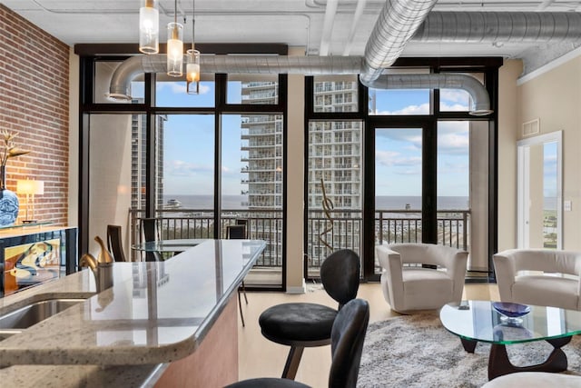 dining space with floor to ceiling windows, a water view, and brick wall