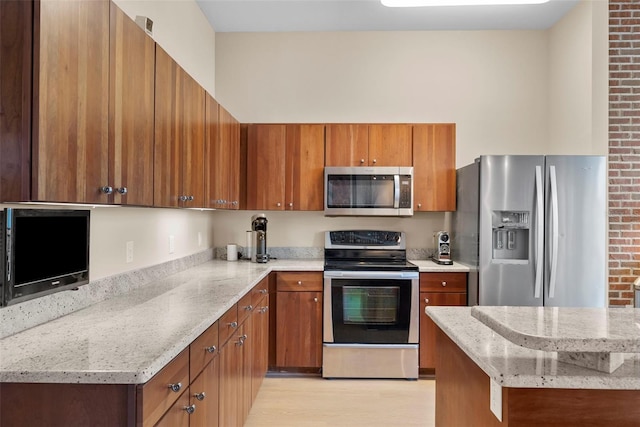 kitchen featuring light stone counters, light wood-type flooring, and appliances with stainless steel finishes