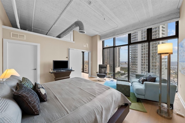 bedroom with ceiling fan, expansive windows, and hardwood / wood-style flooring