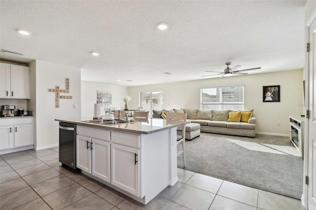 kitchen featuring sink, white cabinetry, an island with sink, a textured ceiling, and stainless steel dishwasher