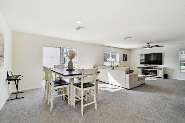 carpeted dining room with ceiling fan