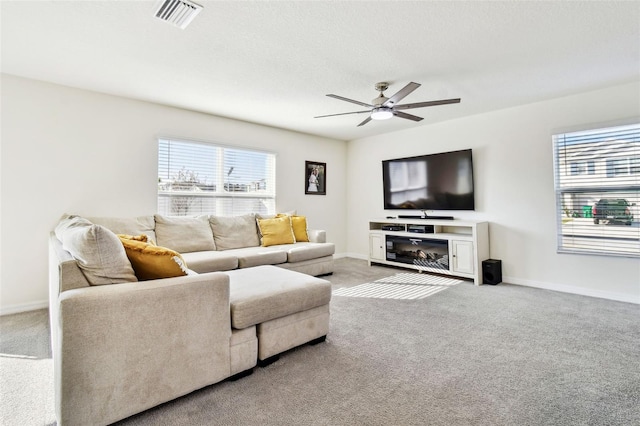 living room with a textured ceiling, a wealth of natural light, ceiling fan, and carpet flooring