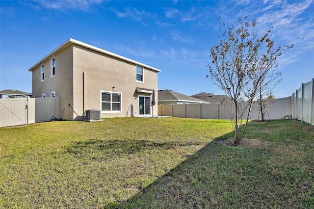 rear view of house with central air condition unit and a lawn