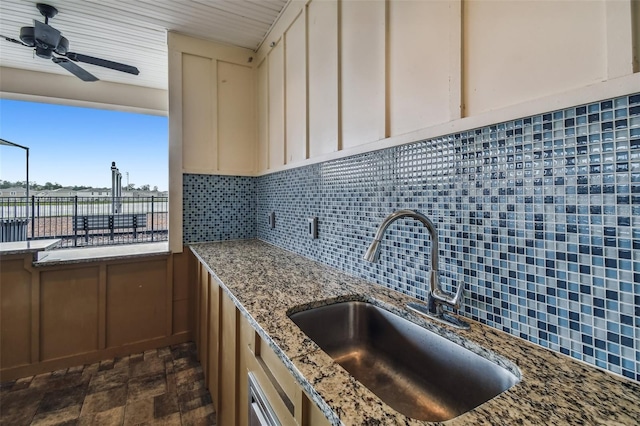 kitchen featuring light stone countertops, sink, decorative backsplash, and cream cabinetry