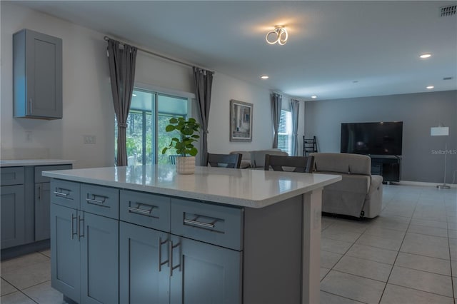 kitchen with a center island, gray cabinets, light tile patterned floors, and a wealth of natural light