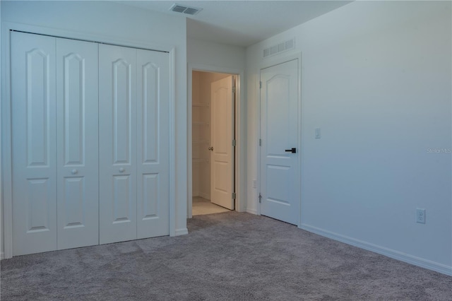 unfurnished bedroom featuring light carpet and a closet