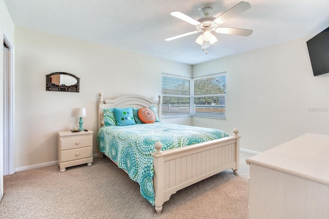 bedroom with ceiling fan, light colored carpet, and a textured ceiling