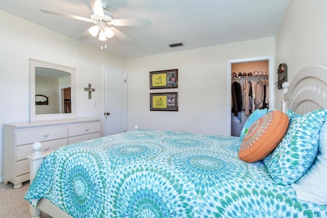 bedroom with ceiling fan, light colored carpet, a closet, and a walk in closet