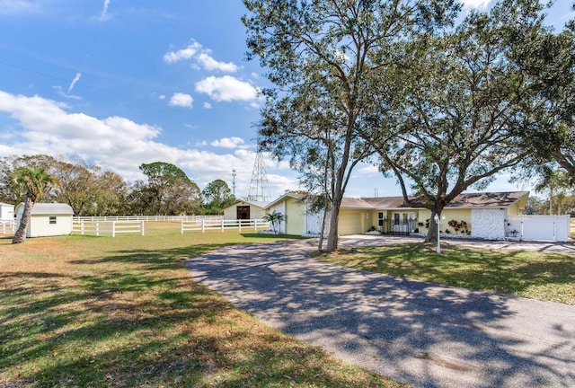 single story home featuring a storage unit and a front lawn