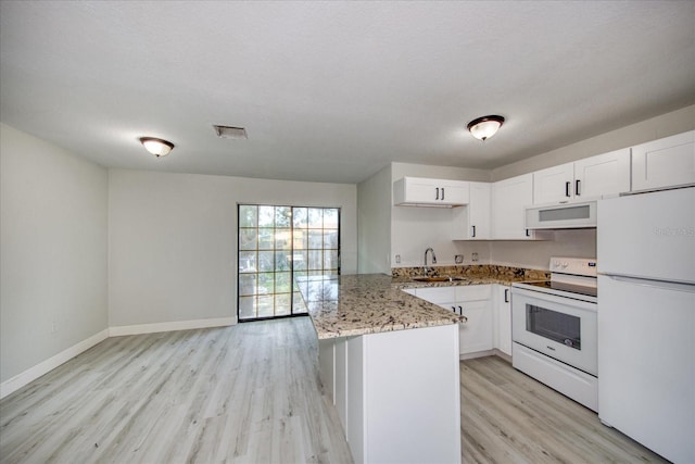 kitchen with kitchen peninsula, light stone counters, white appliances, and white cabinetry