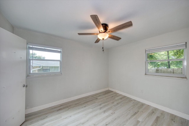 empty room with ceiling fan, plenty of natural light, and light hardwood / wood-style flooring