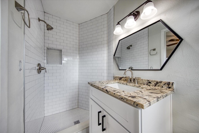 bathroom with vanity and a tile shower