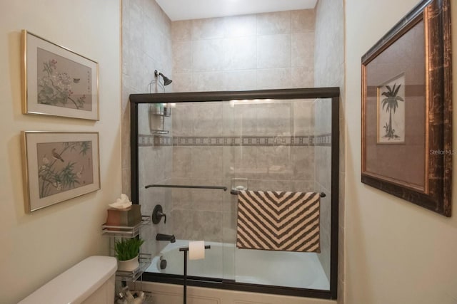 bathroom featuring bath / shower combo with glass door and toilet