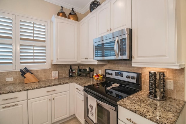 kitchen with white cabinetry, stainless steel appliances, light stone counters, tasteful backsplash, and ornamental molding