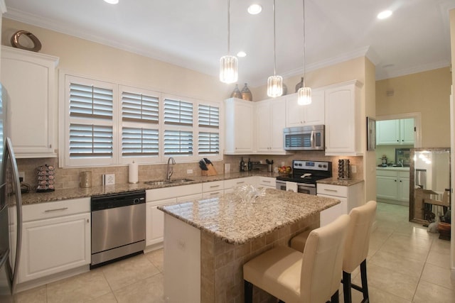 kitchen with a kitchen island, sink, white cabinets, hanging light fixtures, and stainless steel appliances