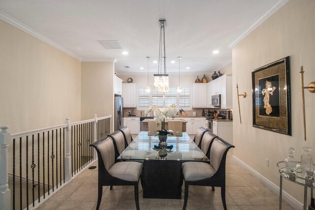 dining area featuring light tile patterned flooring, ornamental molding, and an inviting chandelier