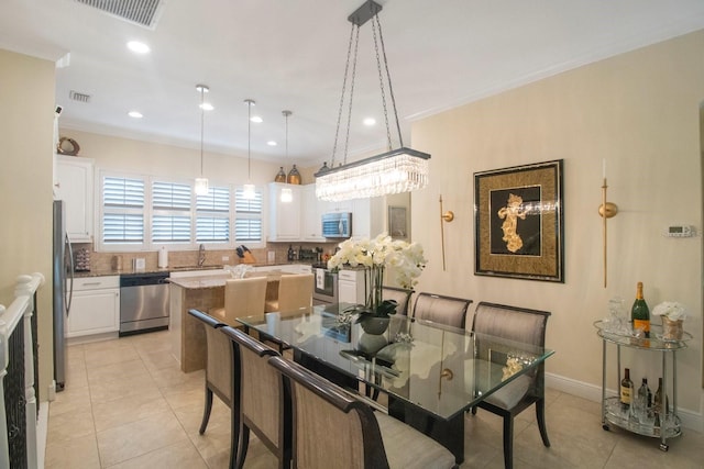 dining area featuring sink, crown molding, and light tile patterned floors