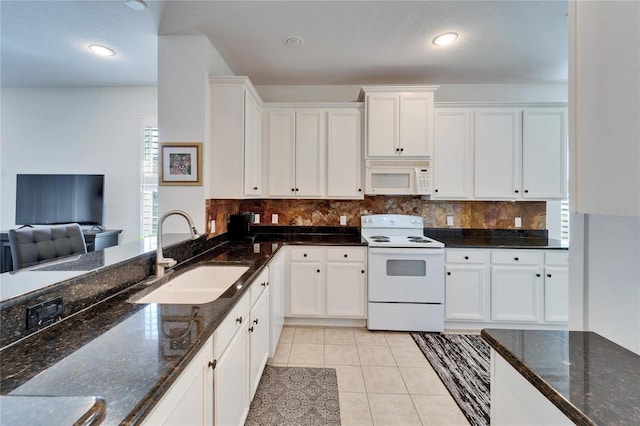 kitchen featuring white appliances, white cabinetry, dark stone countertops, and sink