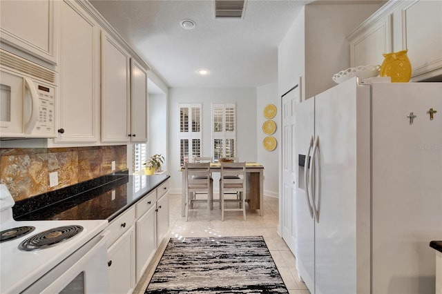 kitchen featuring white appliances, white cabinets, backsplash, and light tile patterned floors