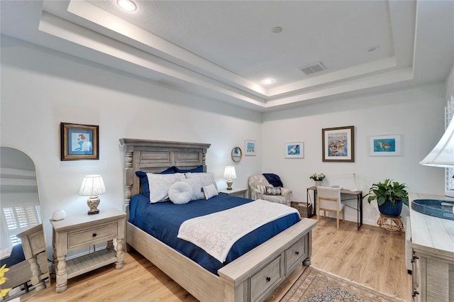 bedroom featuring a raised ceiling and light hardwood / wood-style floors