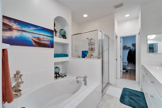 bathroom with built in shelves, tile patterned flooring, plus walk in shower, and vanity