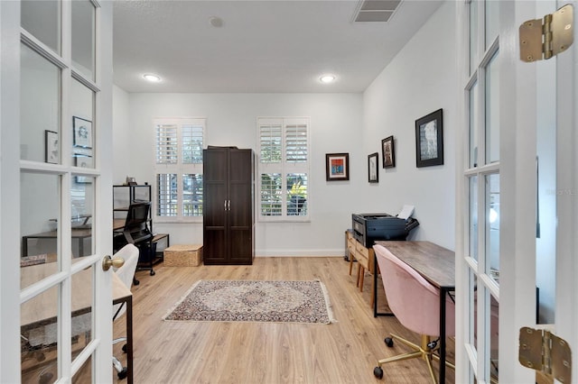 home office with french doors and light hardwood / wood-style floors