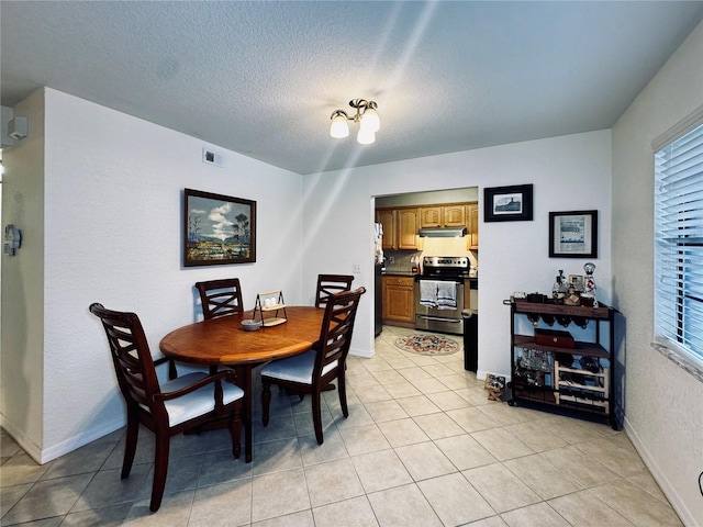 dining area featuring a textured ceiling and light tile patterned flooring