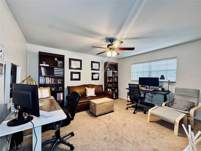 carpeted home office with a textured ceiling and ceiling fan