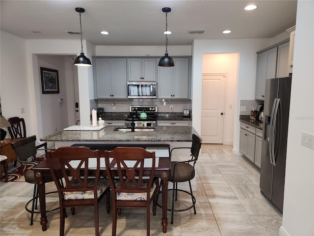 kitchen featuring gray cabinetry, stainless steel appliances, and a breakfast bar area