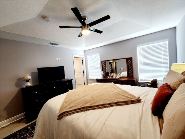 carpeted bedroom with ceiling fan, lofted ceiling, a raised ceiling, and multiple windows