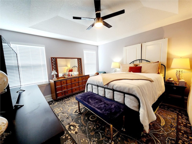 bedroom featuring a textured ceiling, ceiling fan, lofted ceiling, and a raised ceiling