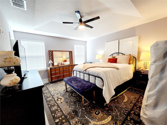 bedroom with ceiling fan, a textured ceiling, and a raised ceiling