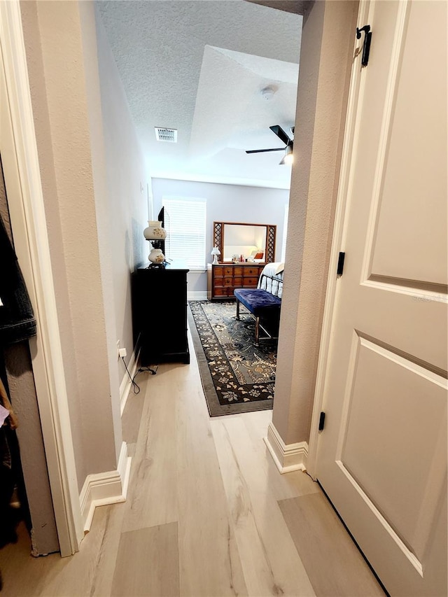 corridor featuring a textured ceiling and light hardwood / wood-style flooring