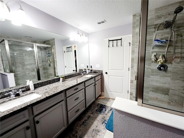 bathroom featuring an enclosed shower, vanity, and a textured ceiling