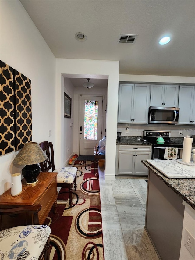 kitchen featuring appliances with stainless steel finishes, dark stone countertops, and gray cabinetry