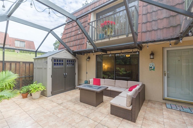 view of patio / terrace with a lanai, a storage unit, a balcony, and an outdoor living space with a fire pit