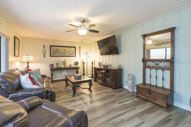 living room featuring ceiling fan, a textured ceiling, and hardwood / wood-style flooring