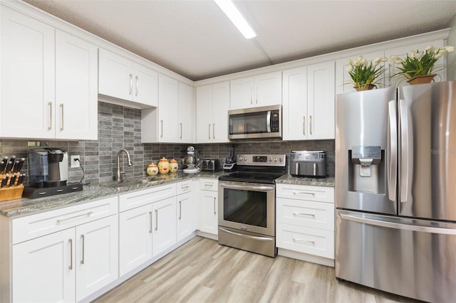 kitchen featuring light stone countertops, sink, white cabinetry, and stainless steel appliances