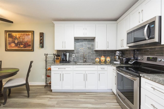 kitchen with sink, white cabinets, dark stone counters, and appliances with stainless steel finishes