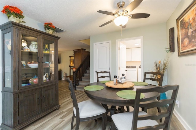 dining space featuring a textured ceiling, light wood-type flooring, washer and clothes dryer, and ceiling fan