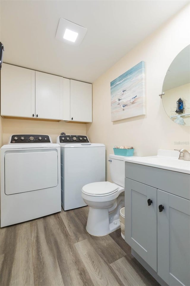 bathroom with wood-type flooring, washer and clothes dryer, and sink