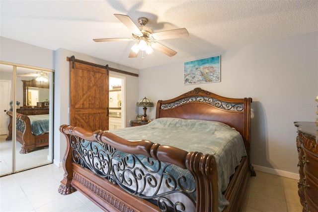 bedroom featuring ceiling fan, a barn door, a textured ceiling, connected bathroom, and a closet