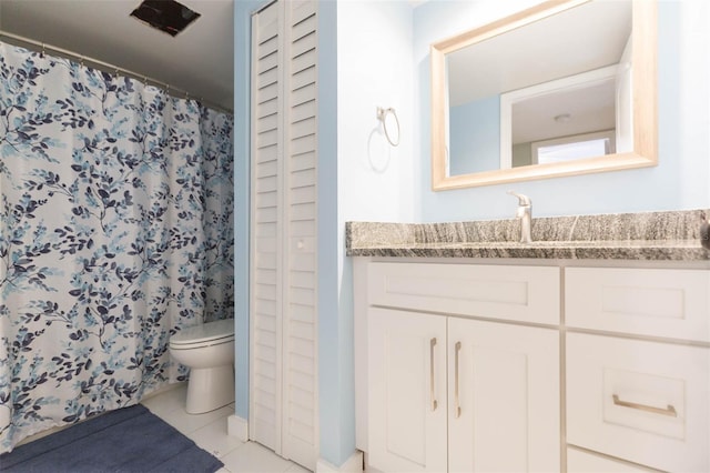 bathroom with toilet, vanity, and tile patterned floors