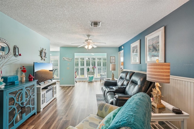 living room with wood-type flooring, a textured ceiling, and ceiling fan