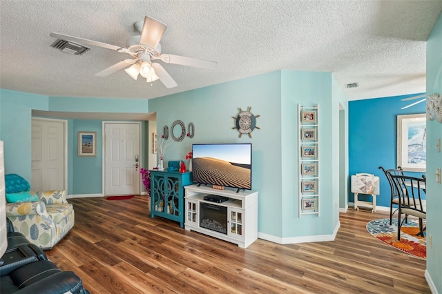 living room with a textured ceiling, ceiling fan, and dark hardwood / wood-style floors