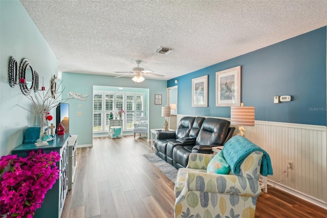 living room featuring wood-type flooring, a textured ceiling, and ceiling fan