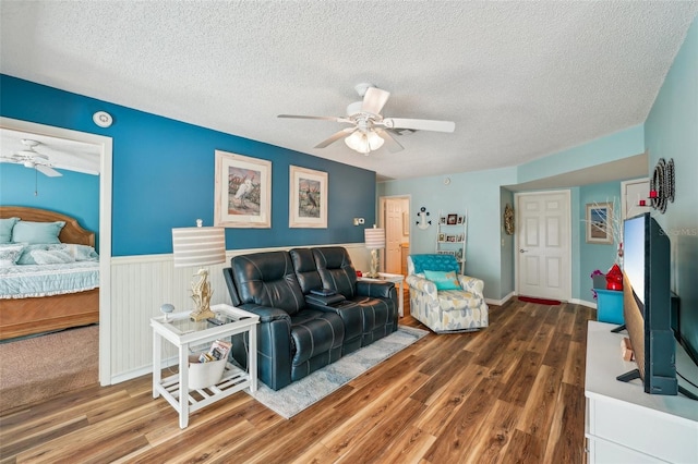 living room featuring a textured ceiling, ceiling fan, and dark wood-type flooring